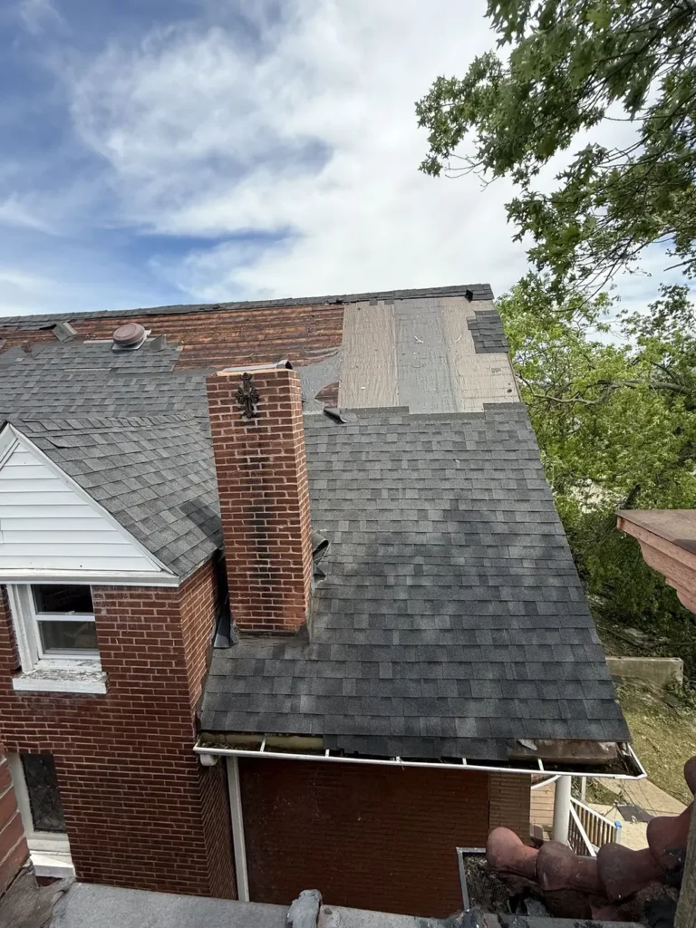 Storm-damaged shingles next to a brick chimney on a St. Louis City home during a Meridian roof inspection