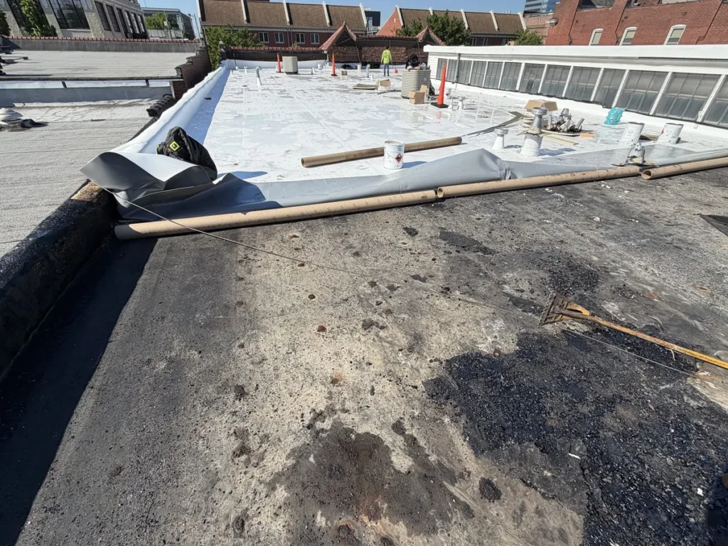 TPO flat roof membrane being installed on a St. Louis City building with brick rowhouses behind it